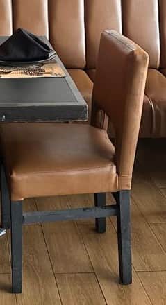 A modern upholstered dining chair featuring a padded brown faux leather seat and a gently curved bac… — 3D model
