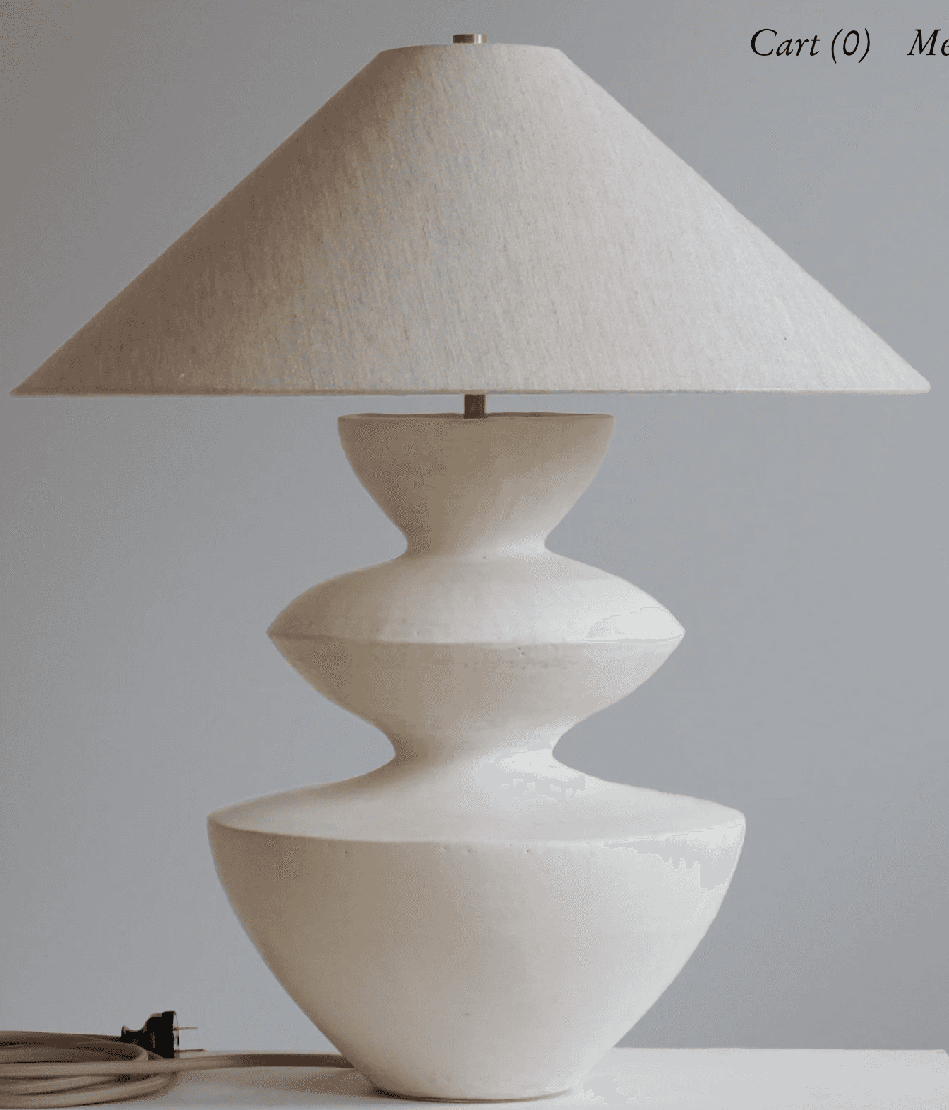 A modern sculptural table lamp featuring an off-white conical fabric shade atop a similarly colored,… — 3D model
