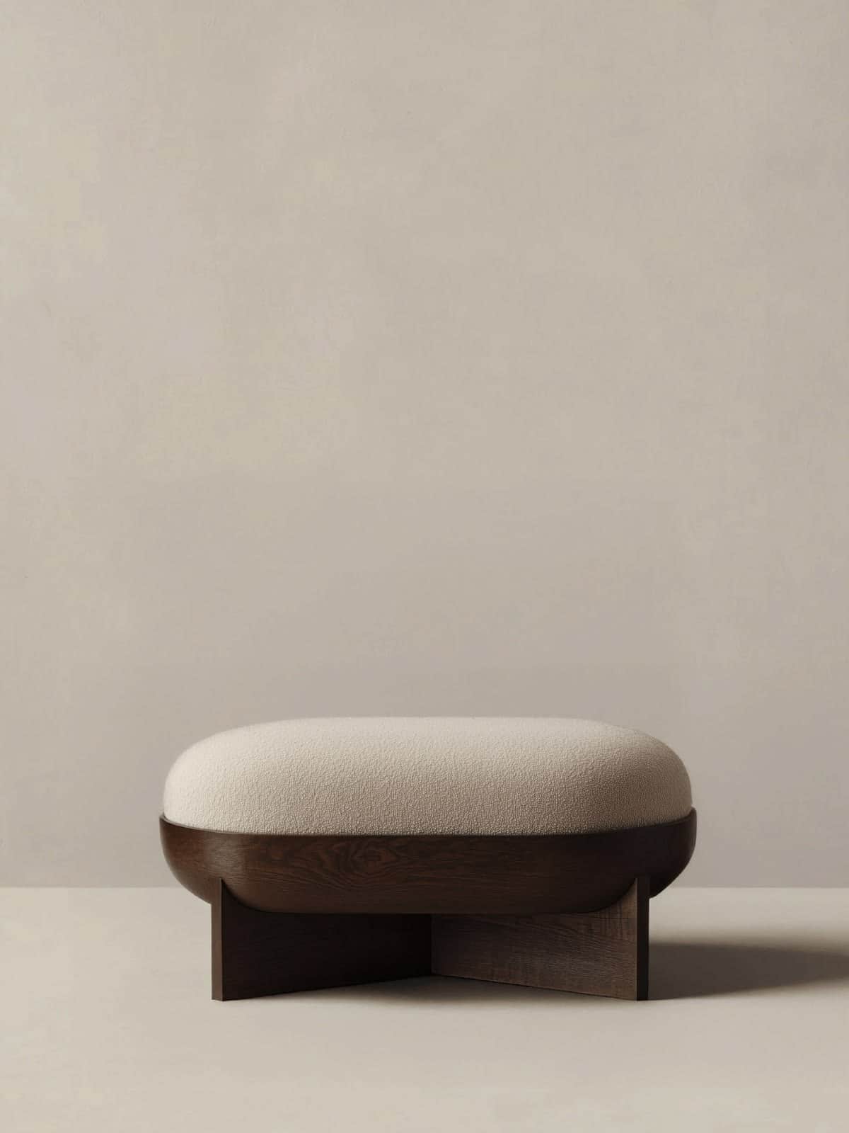 An oval-shaped ottoman with a plush, light-colored boucle upholstered top and a distinctive, dark-st… — 3D model