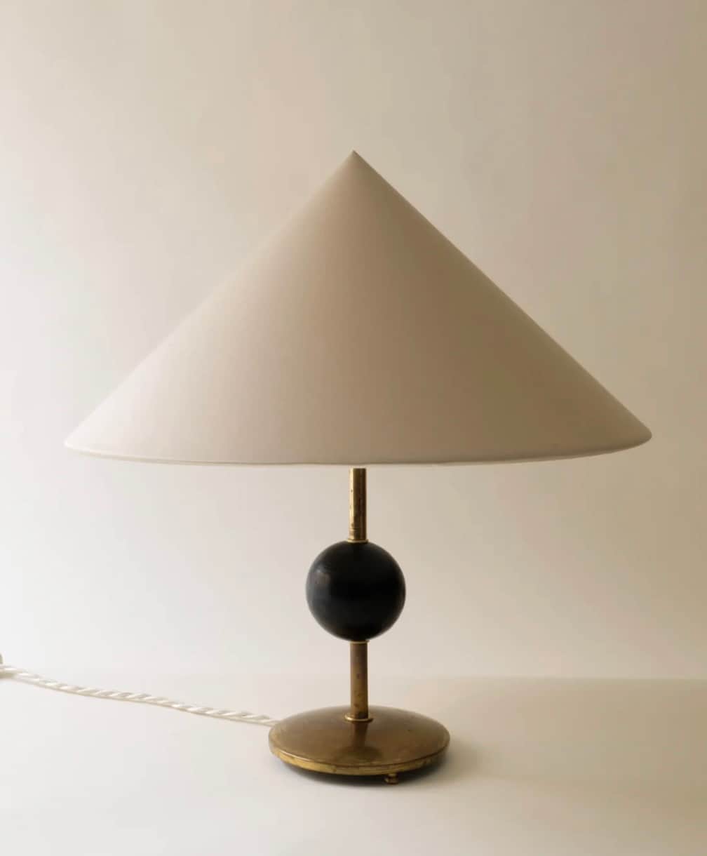 A refined table lamp featuring a wide, cream-colored conical shade. The lamp's stem connects to a da… — 3D model