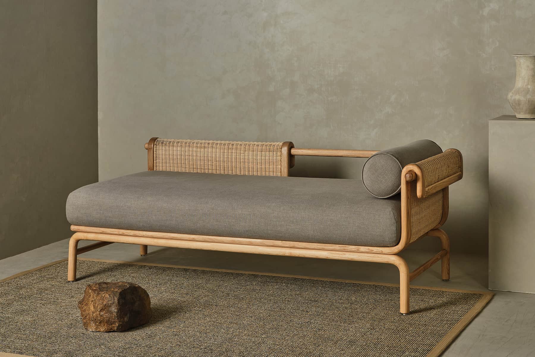A contemporary daybed featuring a light-toned wooden frame, woven rattan detailing on one side, and… — 3D model