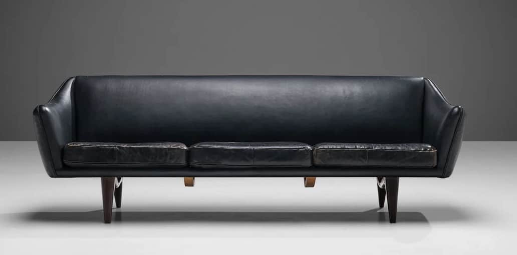 A three-seater sofa with a curved backrest and armrests, upholstered in dark leather. The seat is co… — 3D model