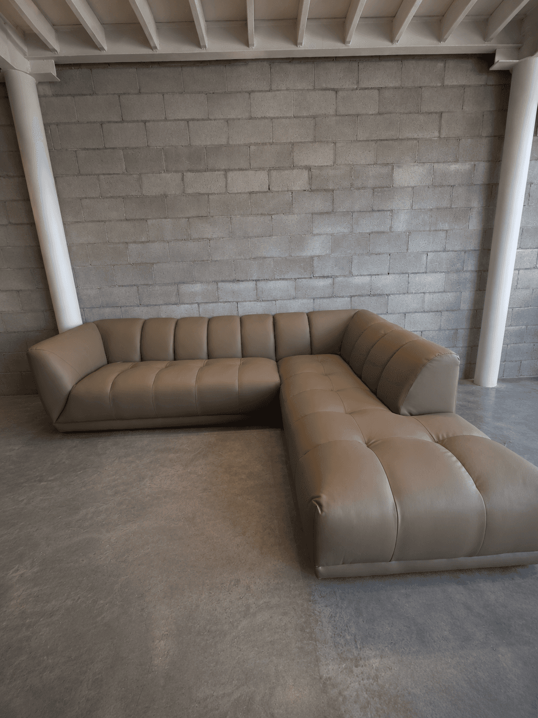 An L-shaped modern sectional sofa upholstered in taupe-colored leather or faux leather, featuring di… — 3D model