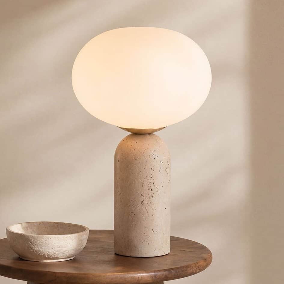 A modern table lamp featuring a cylindrical base made of textured, light-colored travertine, topped… — 3D model
