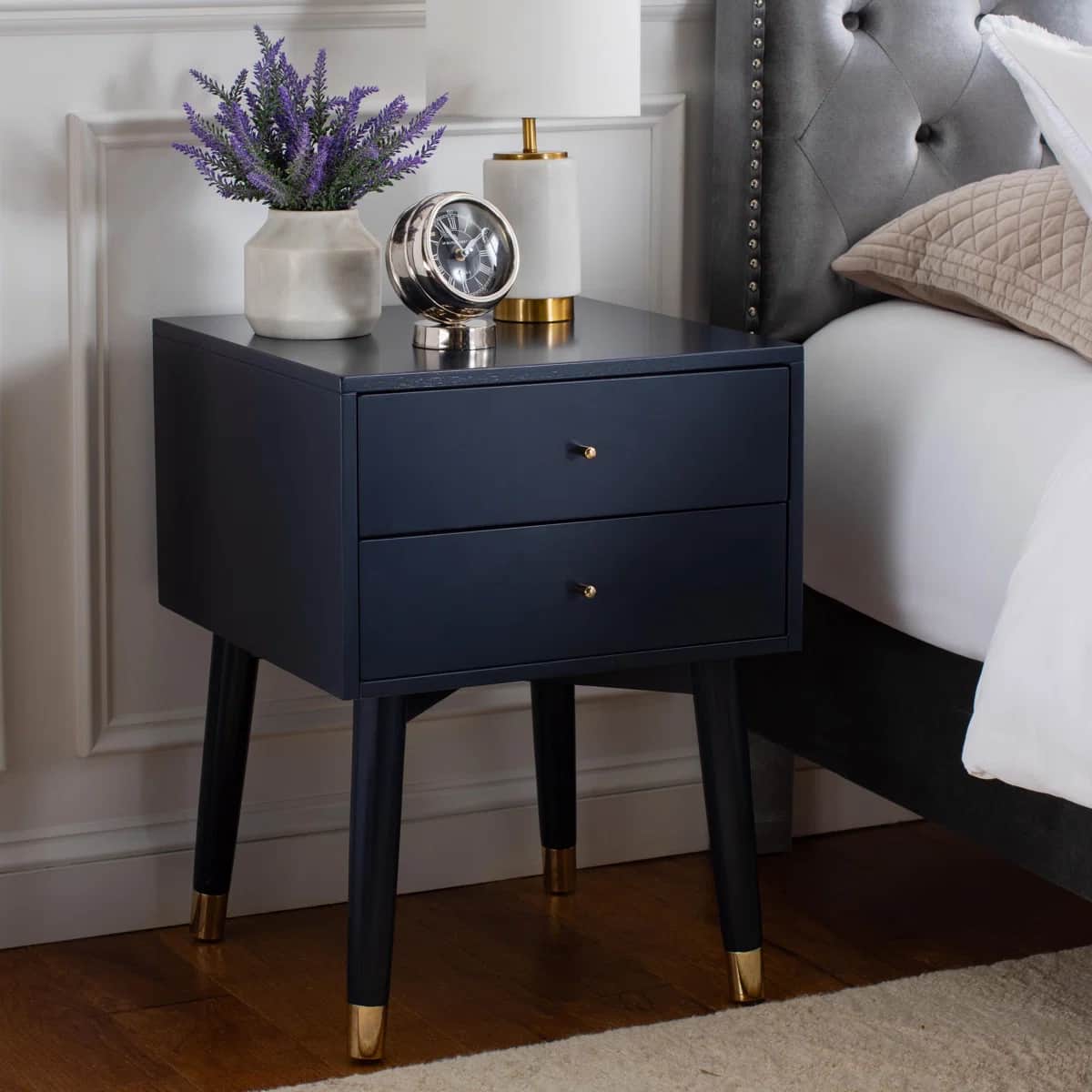 A compact, dark navy blue nightstand featuring two drawers, spherical brass hardware, and four taper… — 3D model
