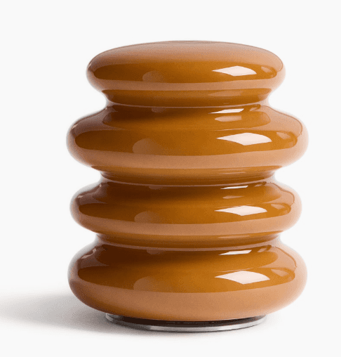A compact, glossy caramel-colored object with a stacked, segmented, cylindrical form, resting on a s… — 3D model