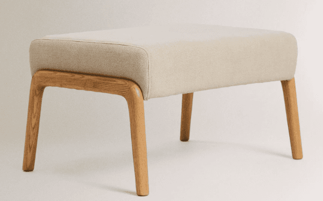 A rectangular ottoman with a cushioned top and four wooden legs. The frame supporting the cushion is… — 3D model