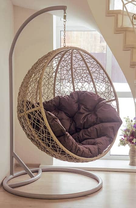 A contemporary egg-shaped hanging chair featuring a beige woven rattan basket suspended from a frees… — 3D model