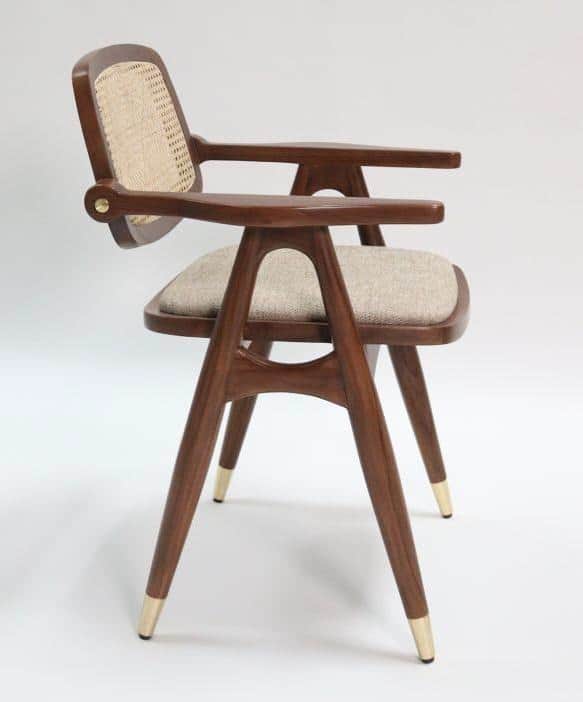 A modern wooden dining armchair featuring a cane back, upholstered seat, and tapered legs with brass… — 3D model