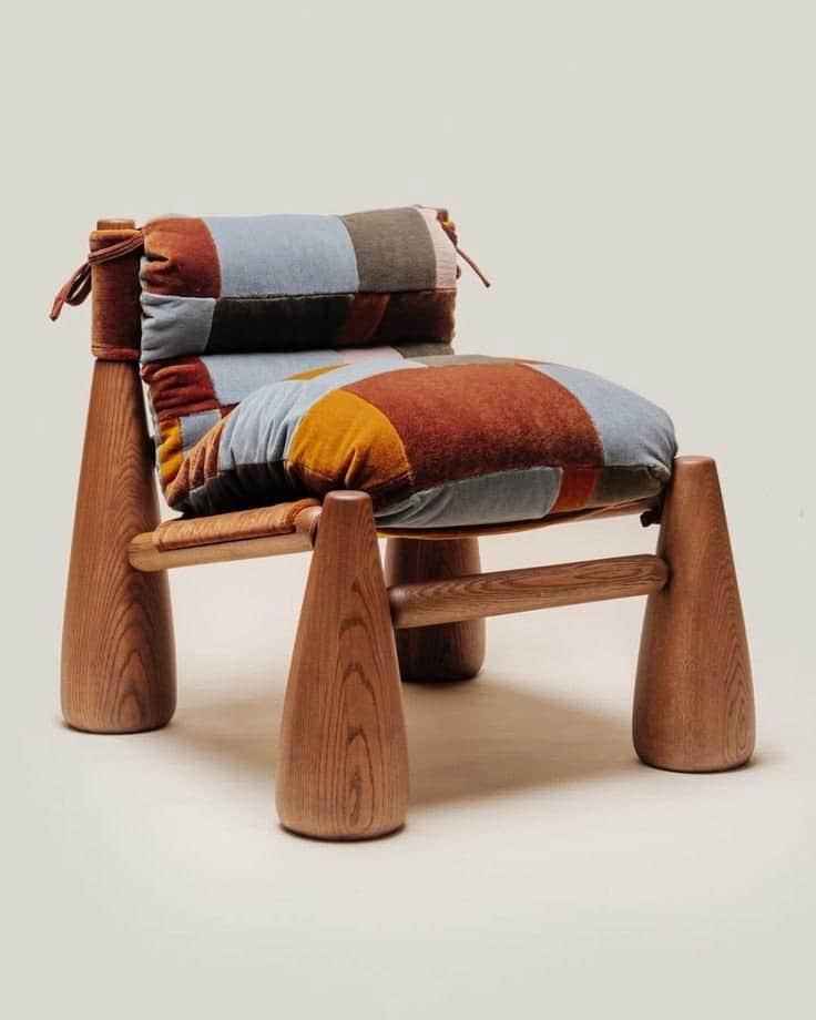 A low-slung lounge chair featuring a sturdy wooden frame with thick, tapered legs and a plush, multi… — 3D model