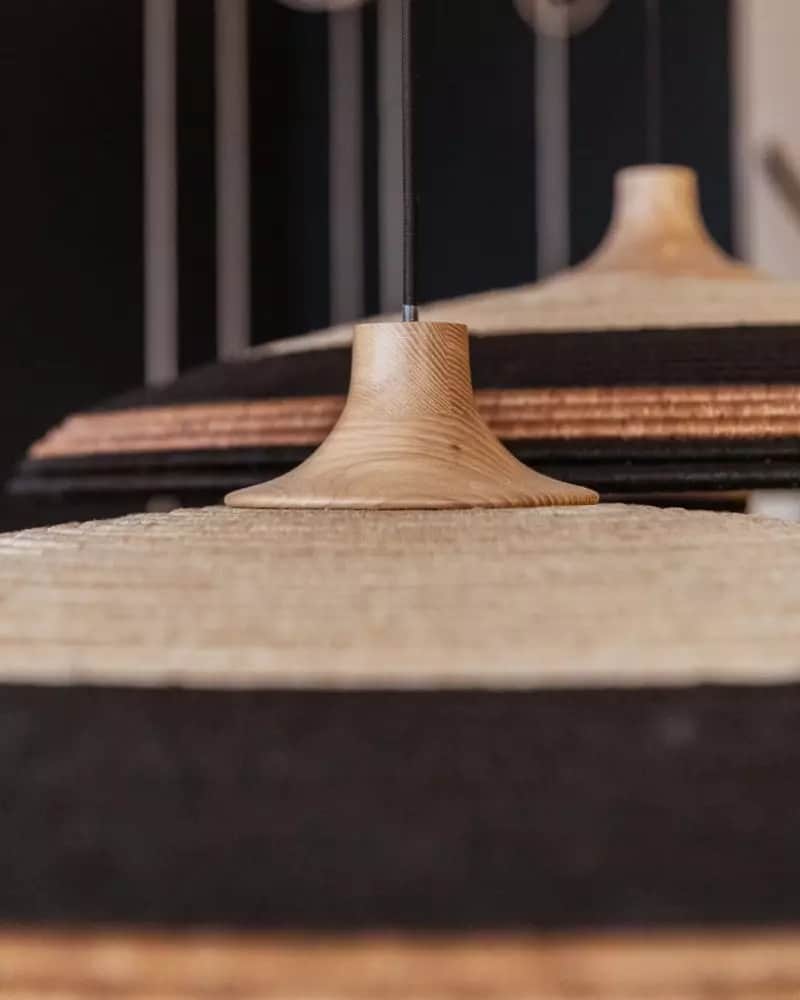 A close-up image of two pendant lights, each featuring a bell-shaped natural wood canopy from which… — 3D model