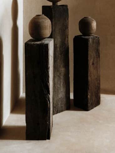 A rustic, dark wooden pedestal with a rough, textured surface, topped with a small, round, terracott… — free OBJ 3D model