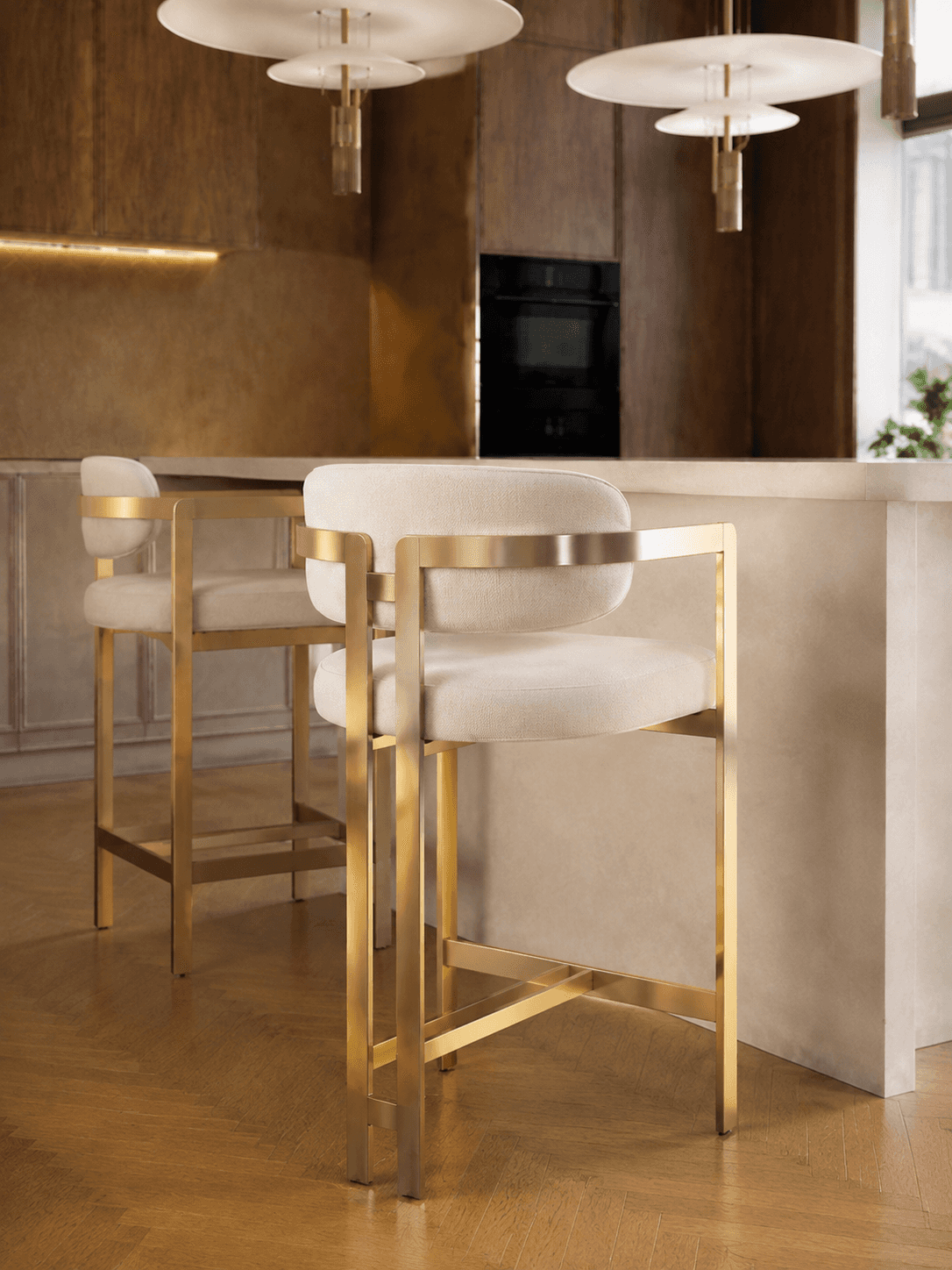 A modern bar stool featuring a sleek gold-finished metal frame and cream-colored upholstered seating… — 3D model