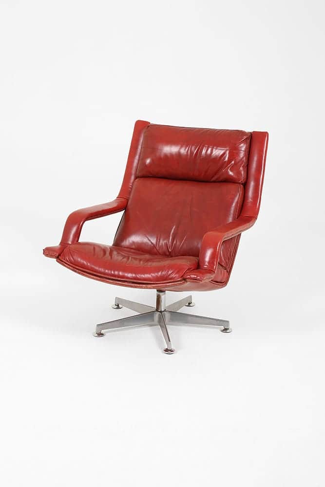 A vintage armchair with a high back and integrated headrest, upholstered in red leather. The chair f… — 3D model