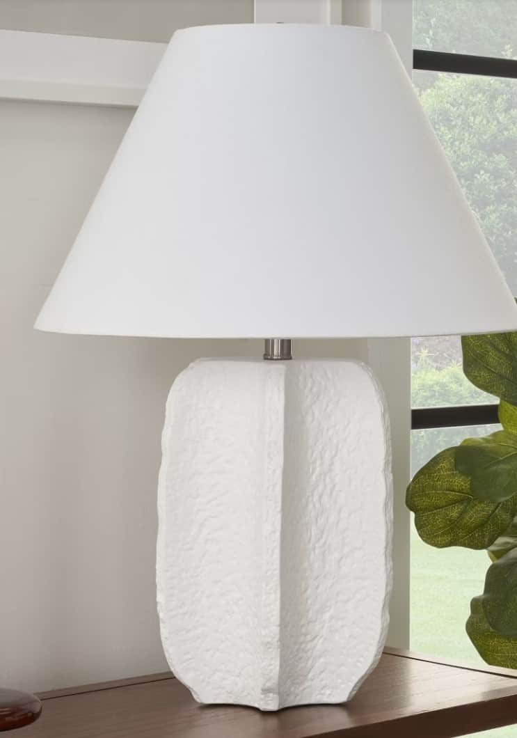 A white table lamp with a conical lampshade and a textured, sculptural base. The base has a rough, o… — 3D model
