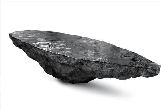 A unique coffee table designed to resemble a floating rock formation with a dark, textured surface,… — free BLEND 3D model