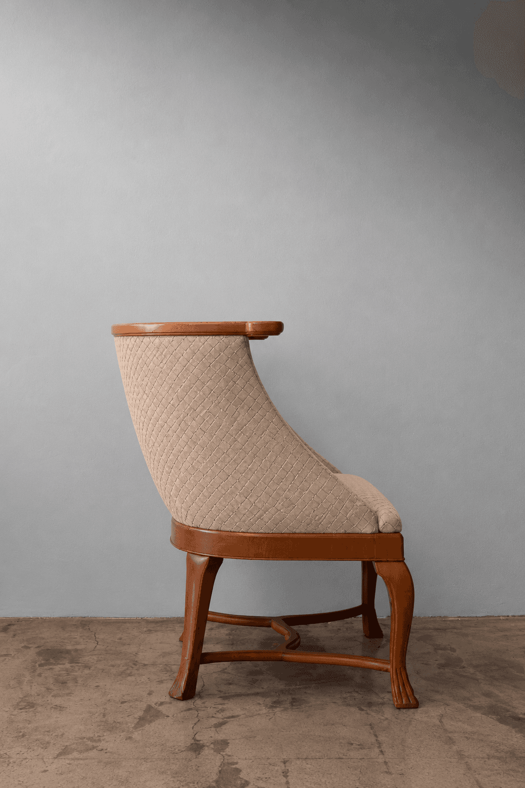 A refined barrel-back armchair featuring a solid wood frame with a polished light brown finish. The… — 3D model
