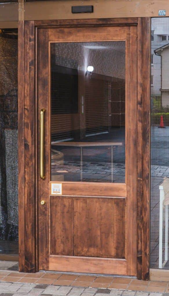A wooden door with a glass pane and a brass handle. The door features a central vertical wooden pane… — 3D model