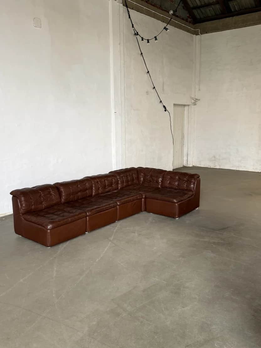 A sectional sofa composed of multiple modular units, upholstered in dark brown tufted material. The… — 3D model