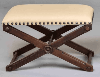 A campaign-style X-frame ottoman featuring a dark wood base and an upholstered seat. The seat is cov… — 3D model