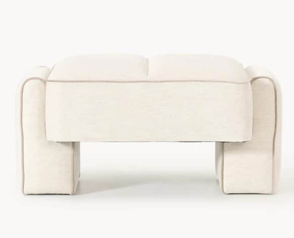 A cream-colored ottoman with a low profile and rounded edges. It features a channel-tufted top and a… — 3D model