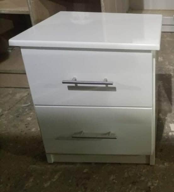 A compact, modern white nightstand featuring two drawers. It has a clean, minimalist design with a f… — 3D model