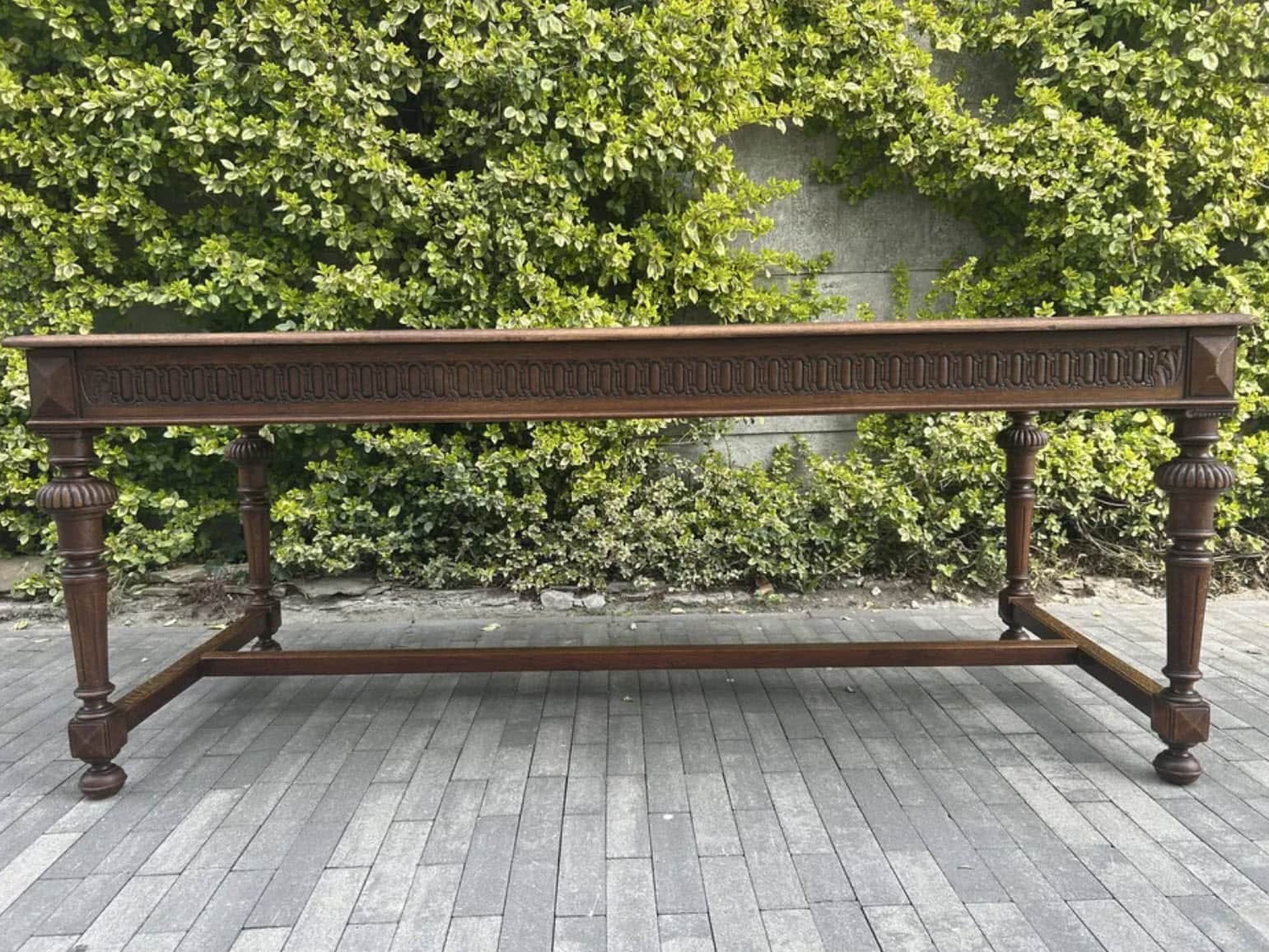A long, narrow dark wood table, featuring a rectangular top and heavily carved apron and turned legs… — 3D model