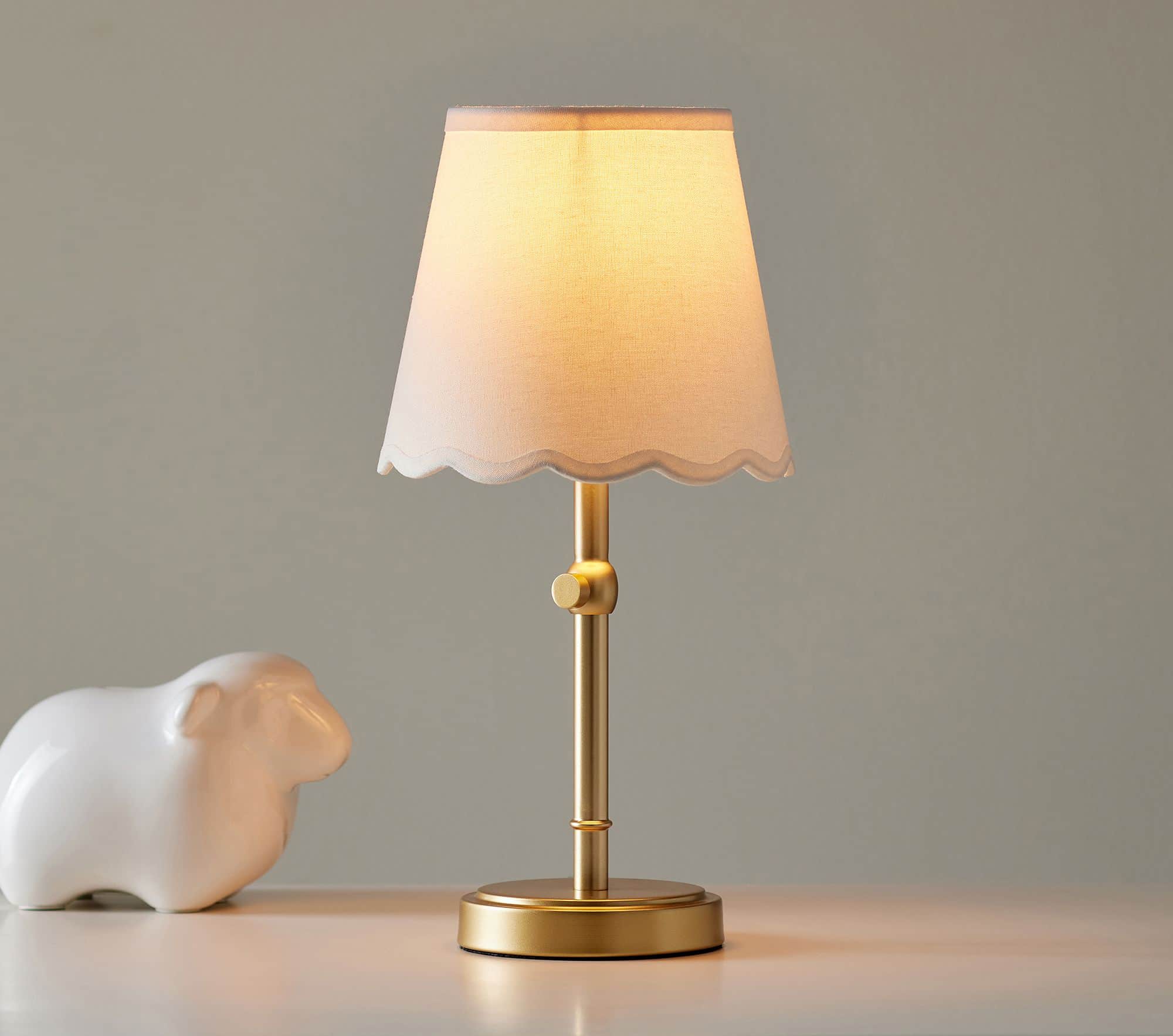 A small table lamp featuring a metallic brass-toned base and stem, supporting a conical linen fabric… — 3D model