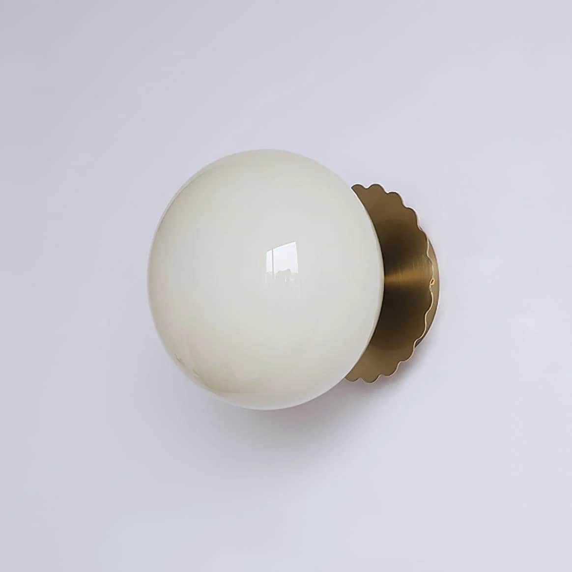 A modern wall-mounted light fixture featuring a spherical opal glass globe diffuser and a scalloped… — 3D model