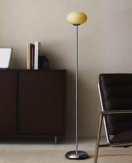 A contemporary floor lamp featuring a polished chrome base and stem, topped with a frosted yellow gl… — 3D model