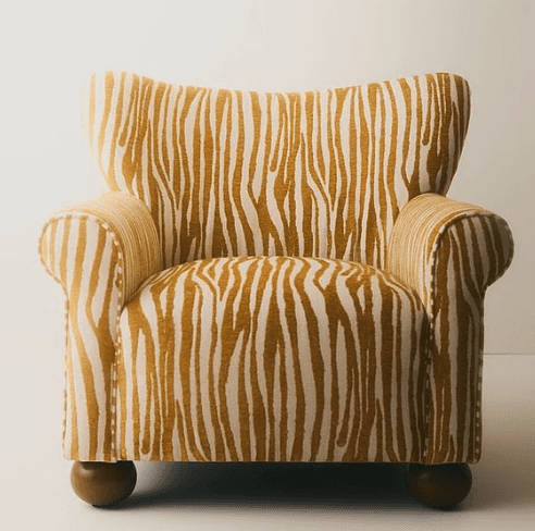 A compact upholstered armchair featuring a distinctive gold and off-white zebra-print fabric. It has… — 3D model