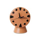 A whimsical, small table clock with a round, terracotta-colored ceramic body featuring abstract blac… — 3D model