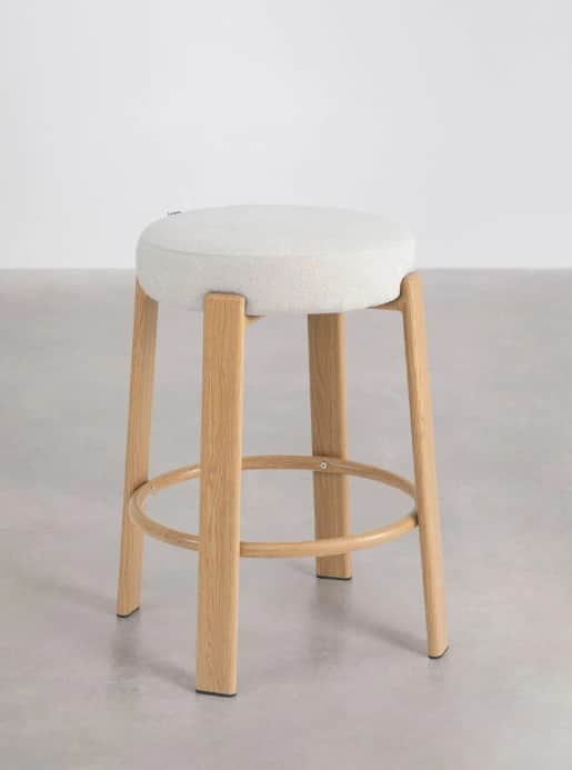 A modern stool featuring a round, light-colored upholstered seat and four splayed wooden legs, conne… — 3D model