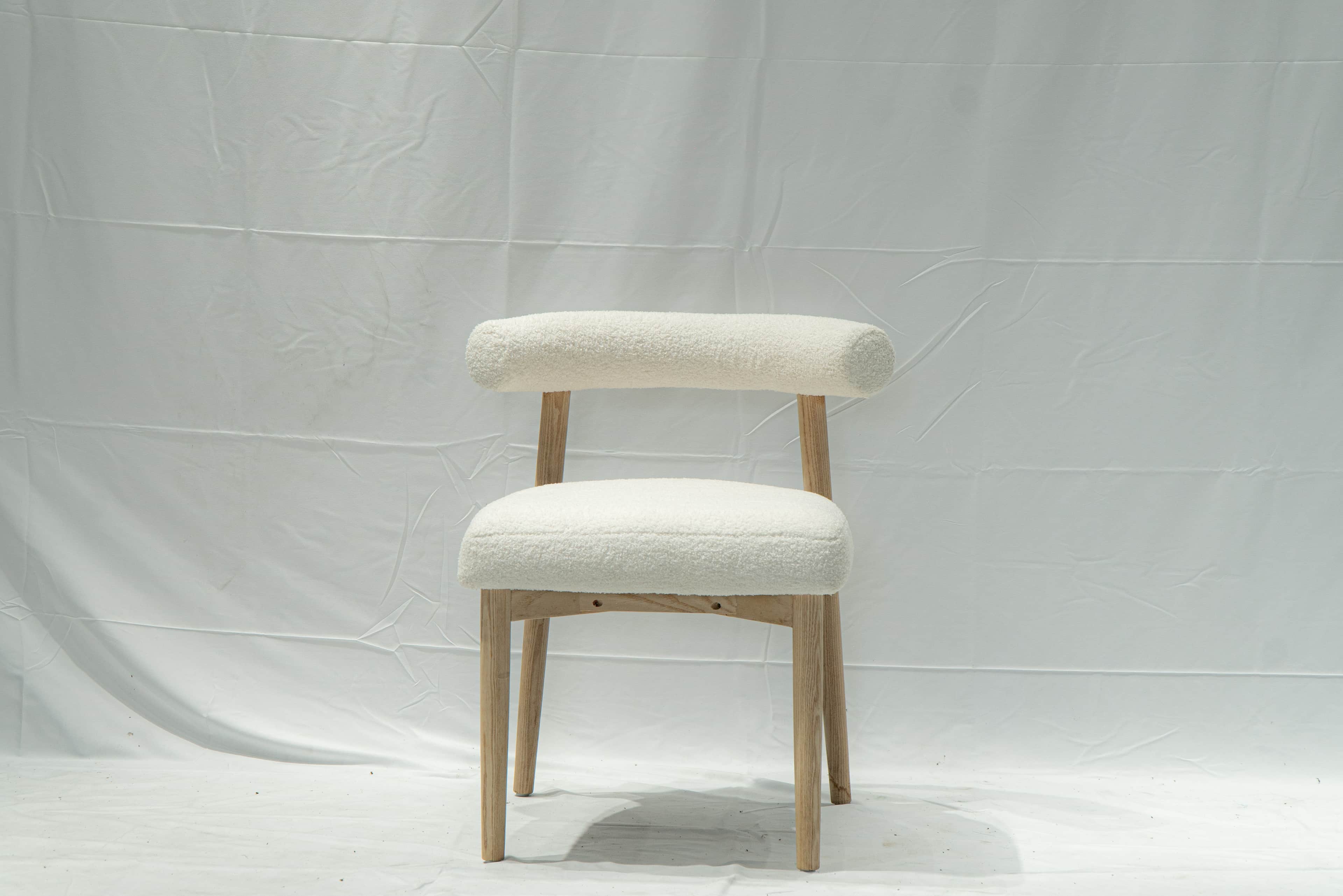A contemporary side chair with a rounded backrest and seat upholstered in a textured, boucle fabric.… — 3D model