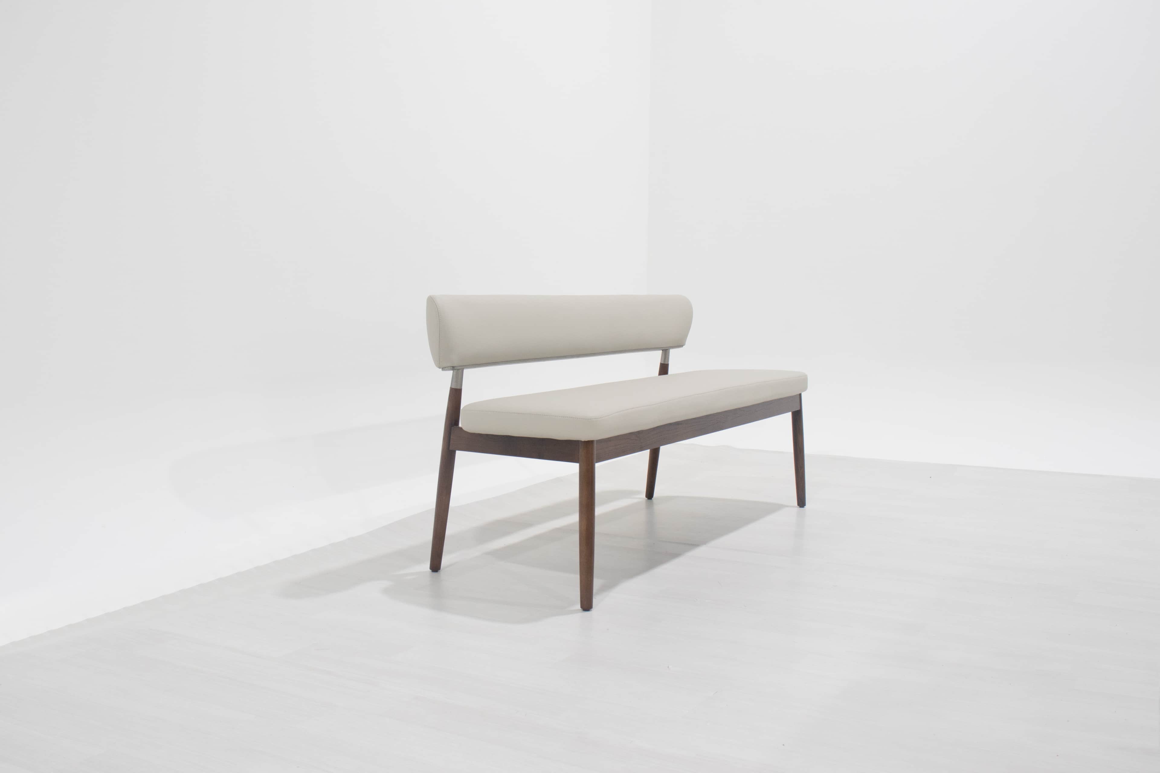 A modern upholstered bench featuring a dark brown wooden frame with tapered legs and a light beige o… — 3D model