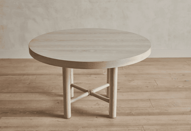 A round, light-colored wooden coffee table with a thick tabletop and four cylindrical legs. The legs… — 3D model
