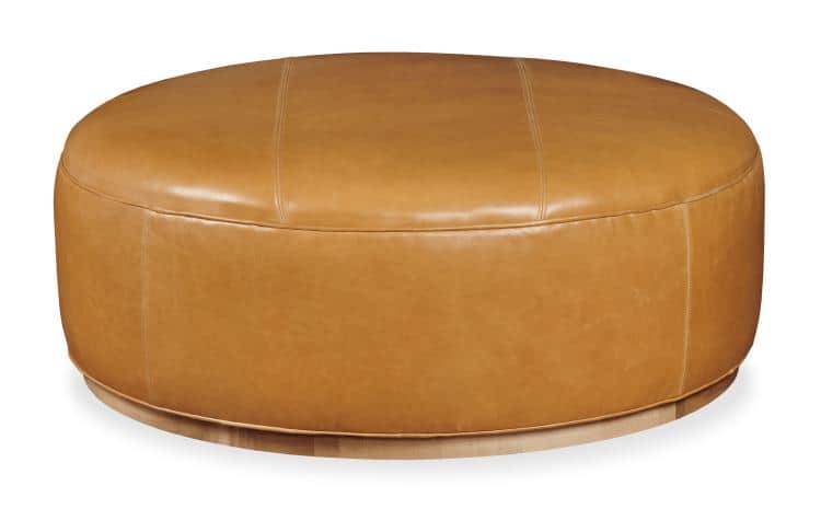 A large, oval-shaped ottoman upholstered in smooth, tan leather. It features subtle stitching detail… — 3D model
