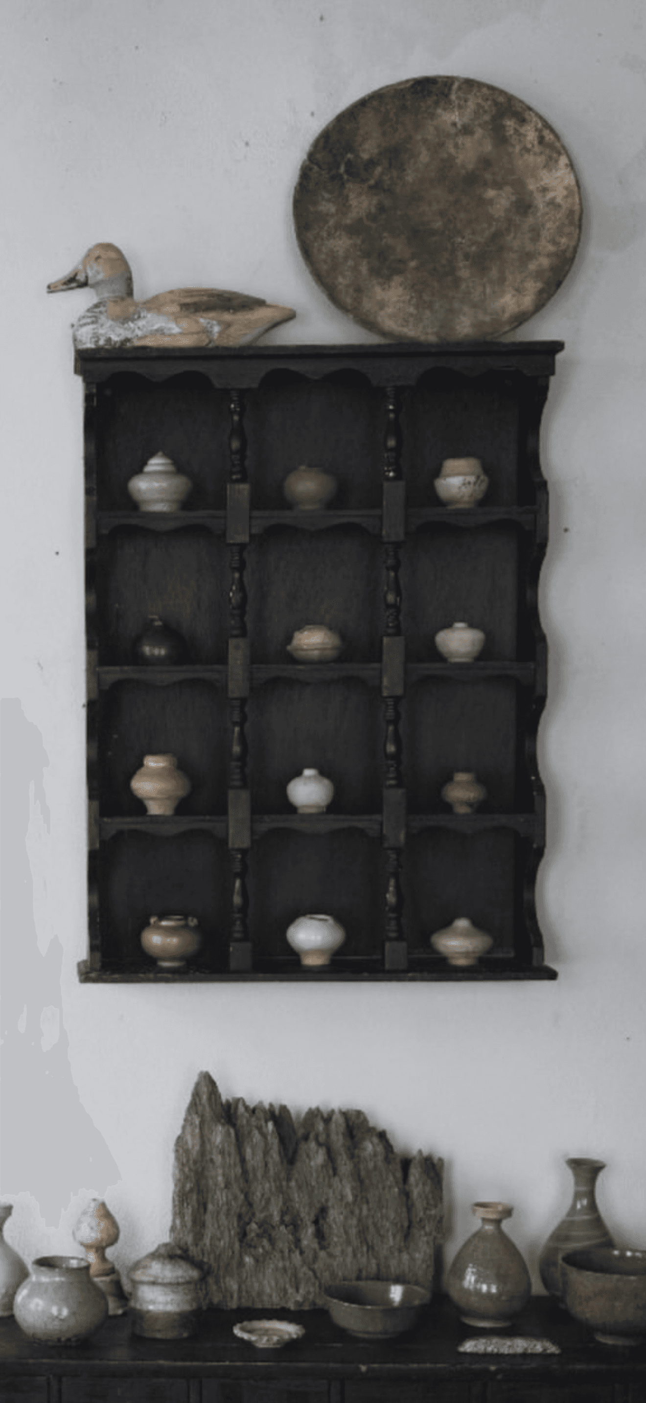 A black, wall-mounted display shelf featuring a tiered structure with scalloped side panels and turned wooden spindles. The shelf unit holds various small, decorative ceramic pots or vases across its multiple levels, designed for showcasing small collectibles. — 3D model