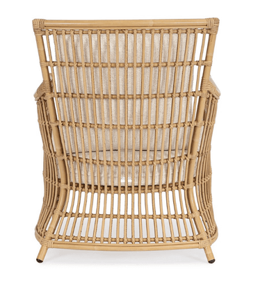 A light brown natural rattan lounge armchair featuring a curved, open-weave frame. It is fitted with thick, removable, light beige upholstered seat and back cushions. The chair has a rounded back and arms, with vertical rattan slats forming the back and side panels. The legs are integrated into the curved frame, with the rear legs slightly flared. The overall aesthetic is natural and relaxed. — 3D model