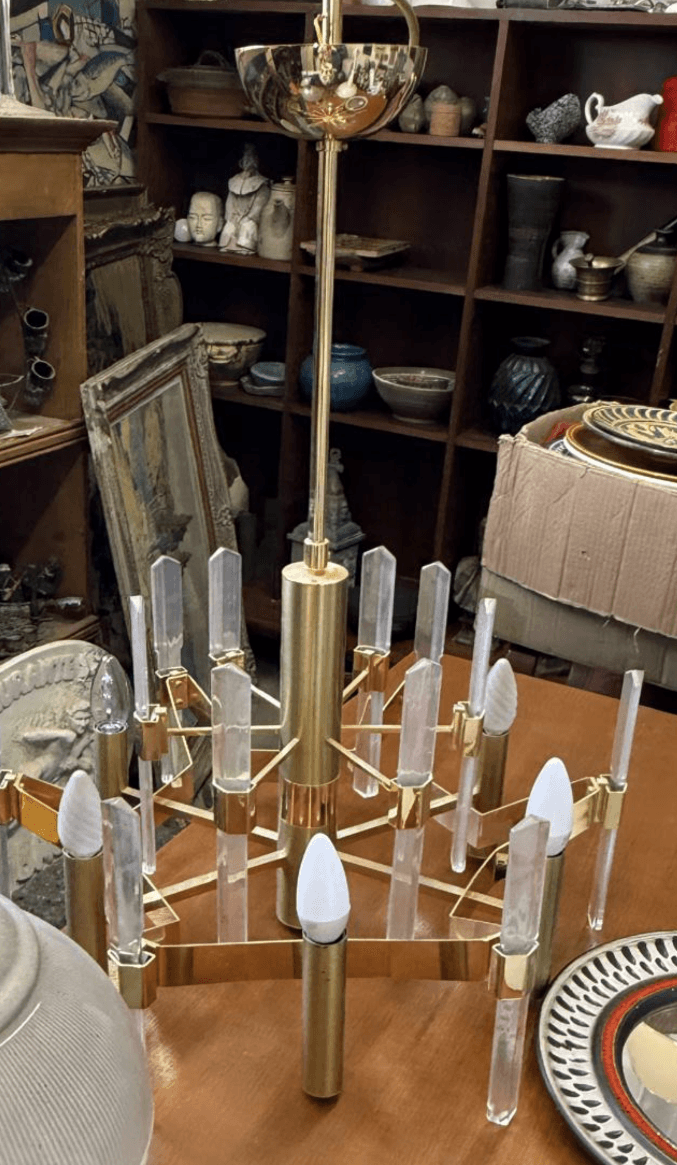 A multi-tiered chandelier with a brass-finished metal frame and clear acrylic elements. It features multiple light sockets designed for candelabra-style bulbs. — 3D model