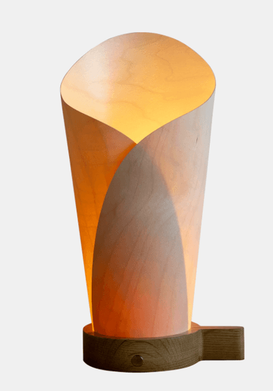 A modern table lamp featuring a sculptural shade crafted from bent plywood or wood veneer, which creates a warm, diffused light. The shade forms an organic, tapering shape, resting on a solid wood base. The design is minimalist and emphasizes natural materials. — 3D model