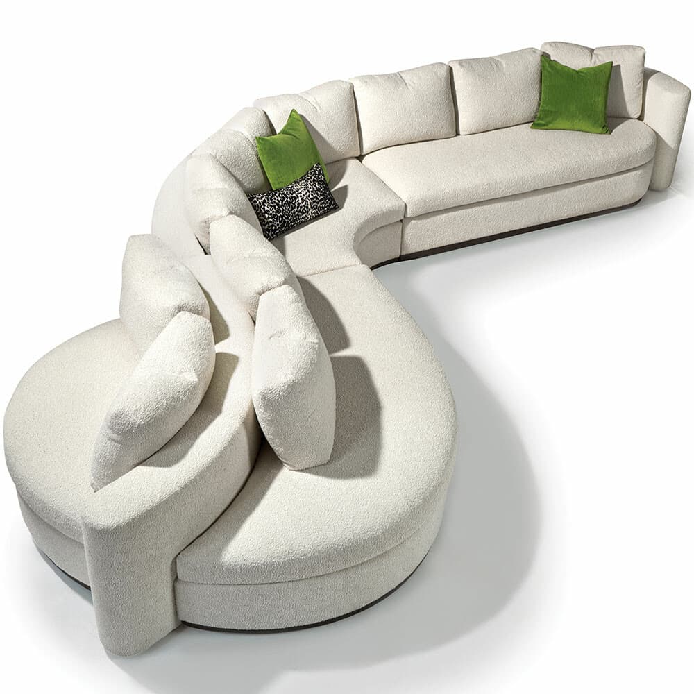 A large, modular, sectional sofa with a curved, organic silhouette. It features a textured, off-white upholstery and several plush throw pillows, two of which are bright green and one with a leopard print pattern. The design is contemporary and emphasizes comfort and flowing lines. — 3D model