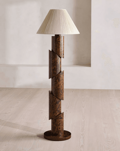 A modernist floor lamp featuring a segmented, cylindrical column base with a burl wood-like pattern, topped with a conical, pleated fabric shade. The base is composed of several cylindrical sections that appear to be cut diagonally and offset, creating a dynamic, spiraling effect. — 3D model