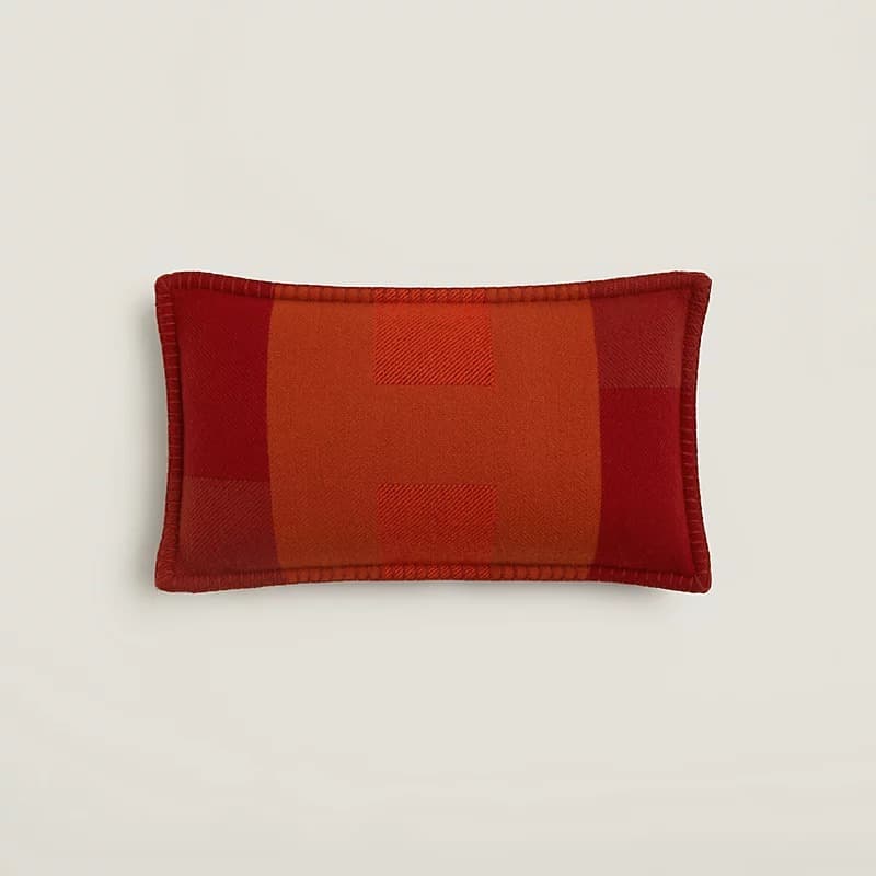 A rectangular decorative pillow featuring a woven wool construction with a prominent plaid pattern in varying shades of red and orange. The edges are finished with a contrasting blanket stitch. — 3D model