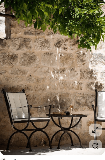 A black wrought iron outdoor armchair featuring a robust metal frame with curved legs and armrests, topped with comfortable white tufted cushions. The cushions have black piping, adding a refined contrast. The chair's design suggests durability and suitability for outdoor environments. — 3D model