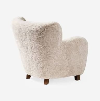 An inviting upholstered armchair featuring a plush cream-colored sheepskin or bouclé fabric, with a rounded silhouette, integrated armrests, and subtle wooden legs. — 3D model