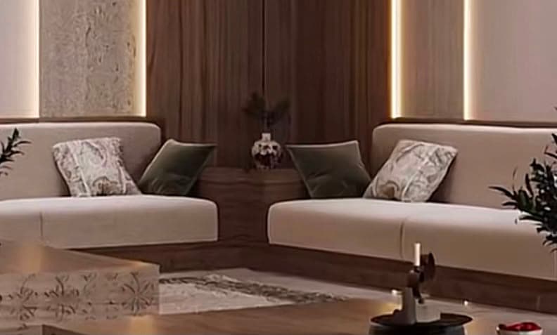 A modern two-seater sofa featuring light beige upholstered cushions and a contrasting dark wood plinth base. The sofa has a clean, minimalist design with squared arms and back. It includes three decorative throw pillows: two dark green solid pillows and one patterned light beige pillow. — 3D model