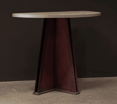 A contemporary console table featuring a grey concrete half-moon shaped top and a sculptural, angular metal pedestal base with a distressed dark red/rust finish. The base is composed of several tapering metal sheets forming a substantial, inverted-pyramid-like structure. — 3D model
