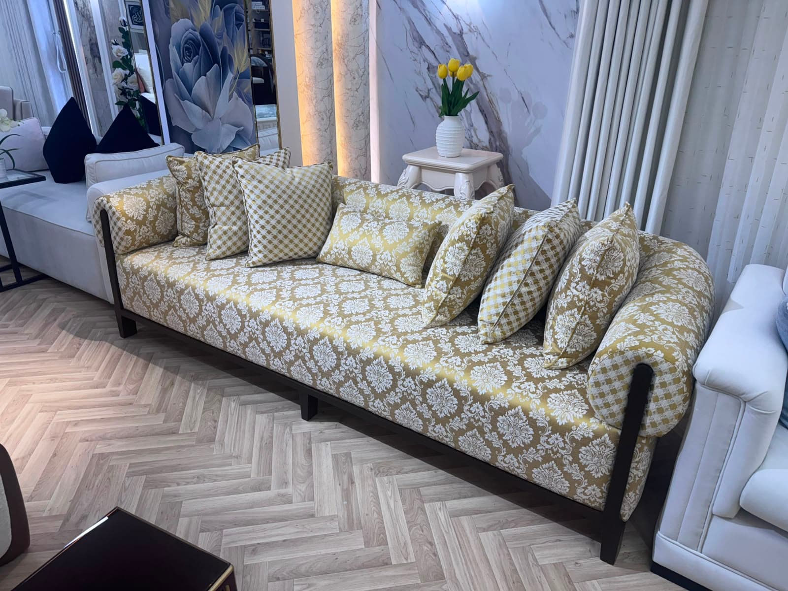 A traditional, ornate upholstered sofa featuring a gold and cream damask pattern, rolled armrests, dark wood frame, and multiple coordinating throw pillows. — 3D model