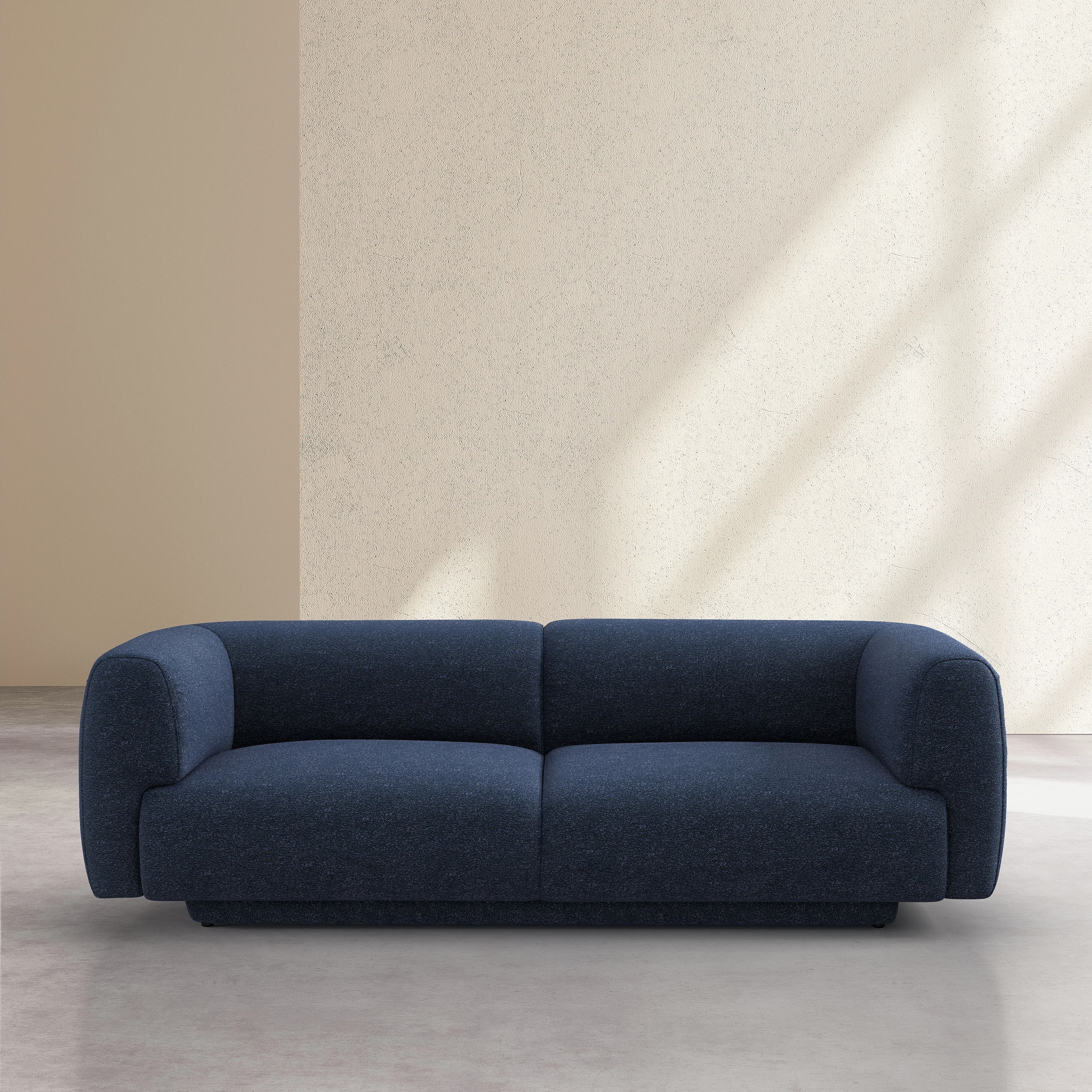 A contemporary two-seater sofa with a low profile and blocky arms. The sofa features a deep seat and a plush appearance, upholstered in a textured navy blue fabric. The design emphasizes clean lines and a minimalist aesthetic, with a distinct separation between the seat cushions. The base is integrated and appears to be part of the overall upholstered structure. — 3D model